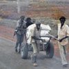 Unidentified men carry away sacks of food looted from the World Food Programme compound in Abyei, Sudan
