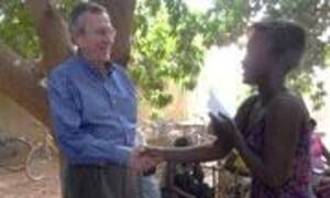 Barack Obama shakes hands with a woman in a rural village in Burkina Faso.