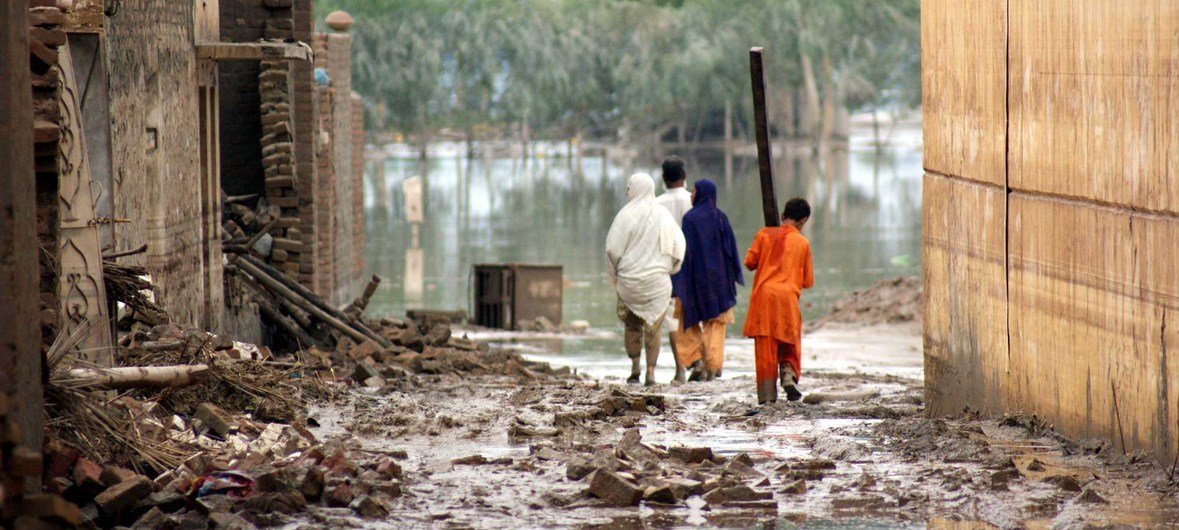 Victims of last year&rsquo;s floods walk the water-filled streets of the city of Nowshera