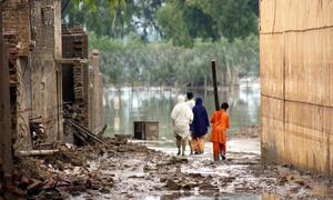 Victims of last year&rsquo;s floods walk the water-filled streets of the city of Nowshera