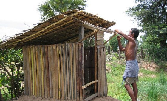 Trabalhador constroi latrina no Cambodja