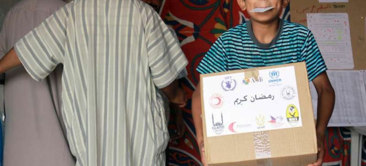 Un jeune réfugié transporte un carton de nourriture pour le repas du soir pendant le Ramadan.