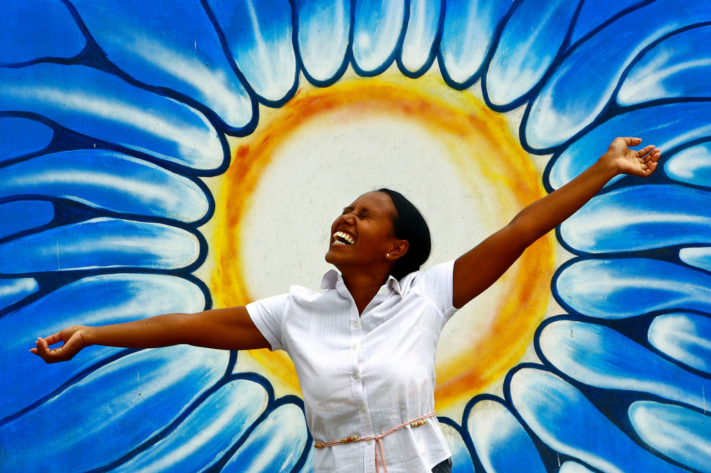 Une femme pose devant un dessin représentant le soleil. Photo 