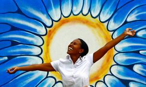 Une femme pose devant un dessin représentant le soleil. Photo 
