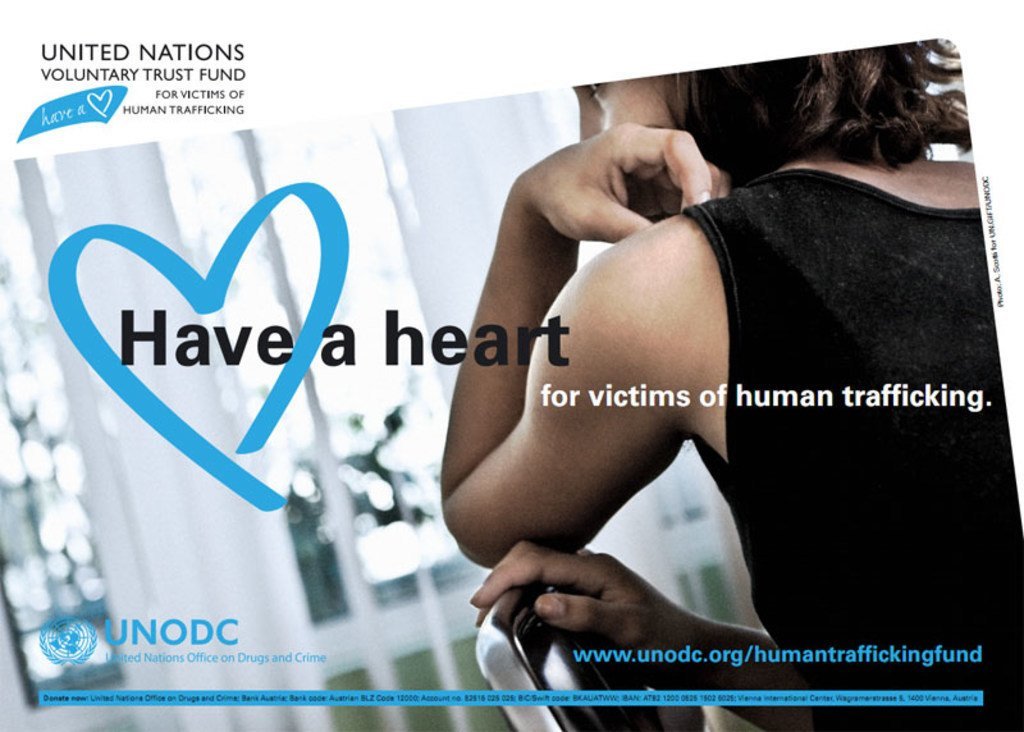 Bango la UNODC linaloonyesha mgongo wa mwanamke akiwa amebeba mikono yake mabegani, lenye maandishi yanayosomeka 'Uwe na moyo kwa waathiriwa wa biashara haramu ya binadamu.'