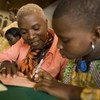 Angélique Kidjo, UNICEF Goodwill Ambassador, and a girl sign a passport in Cotonou, Benin