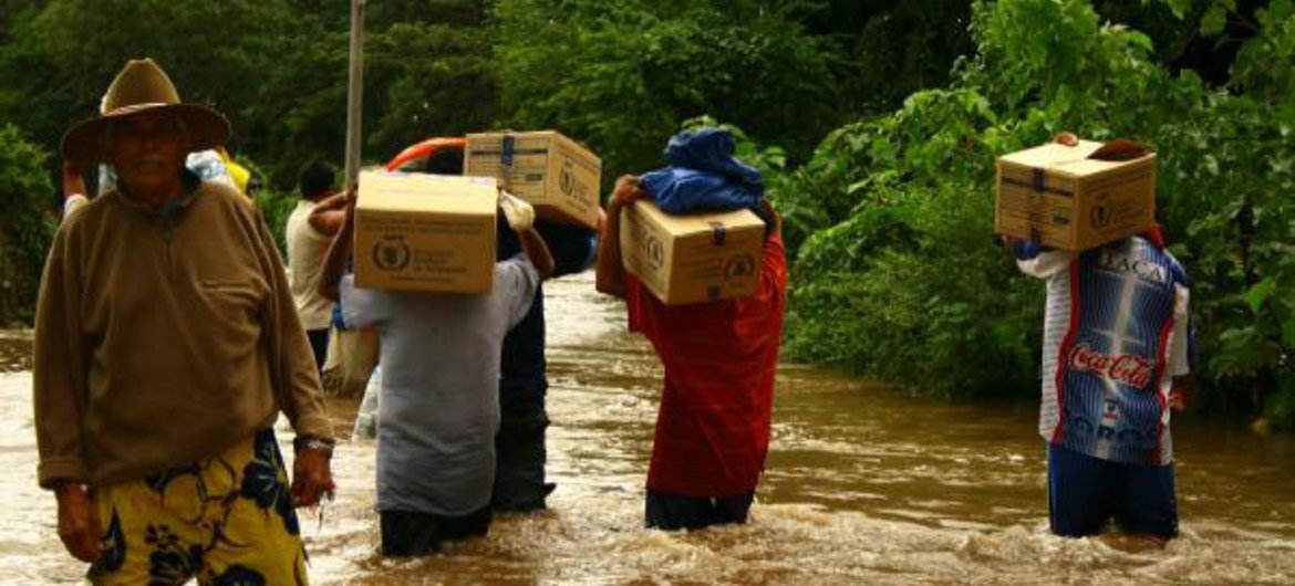 Des résidents de la communauté d'Icaco affectée par les inondations au Salvador transportent des biscuits fournis par le PAM.