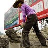 A worker in Wenchuan County, China, severely damaged by an earthquake in 2010, mixing cement at a new government-subsidized housing scheme