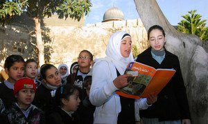 Students at an UNRWA girls’ school in East Jerusalem read in the schoolyard  with the Al-Aqsa mosque in the background.