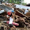 Une femme sauve des biens personnels de son village ravagée par la tempête Washi à Mindanao, aux Philippines.