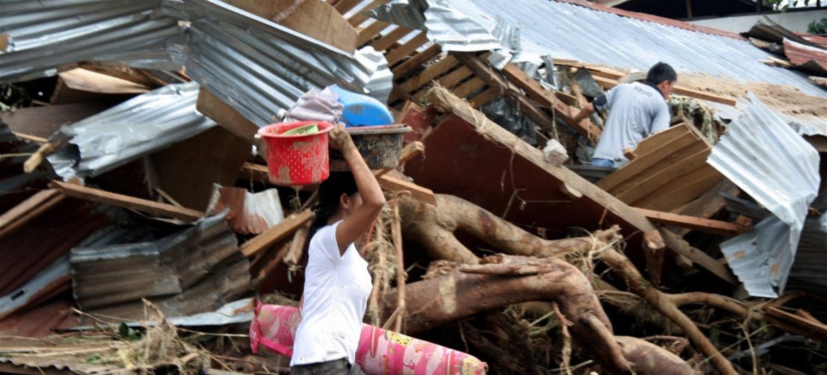 Une femme sauve des biens personnels de son village ravagée par la tempête Washi à Mindanao, aux Philippines.