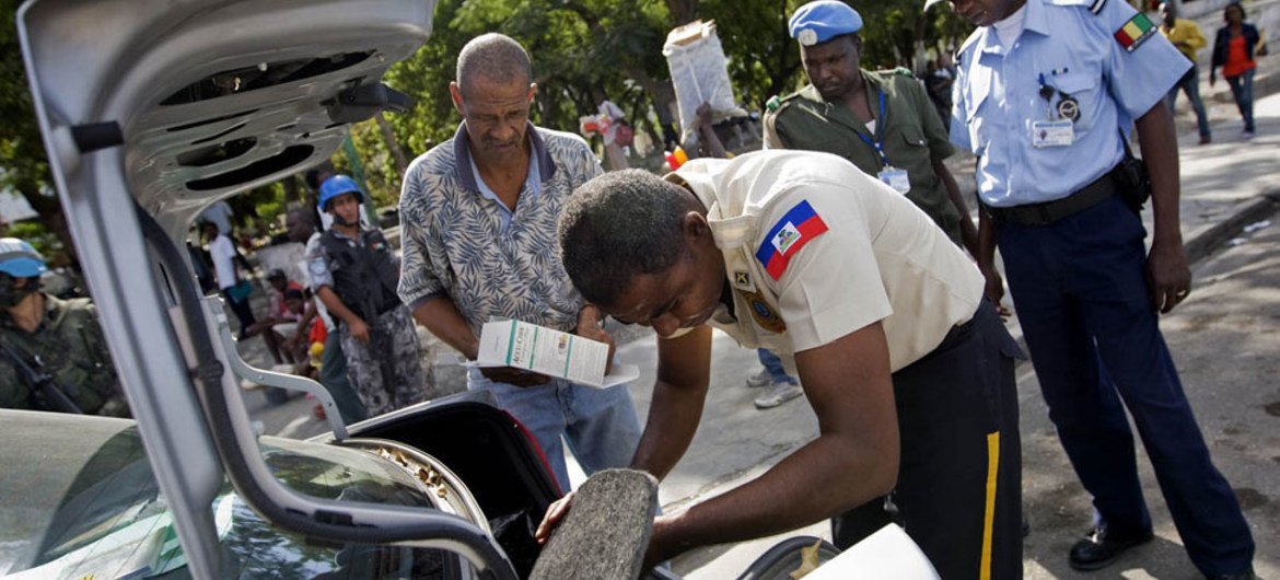 Un officier de la police nationale haïtienne fouille le coffre d'une voiture à Port-au-Prince aux côtés de la Police de l'ONU et de la MINUSTAH.