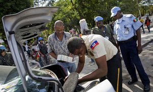 Haitian National Police officer along with UNPOL and MINUSTAH checks the trunk of a car in Port-au-Prince.