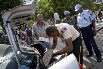 Un officier de la police nationale haïtienne fouille le coffre d'une voiture à Port-au-Prince aux côtés de la Police de l'ONU et de la MINUSTAH.