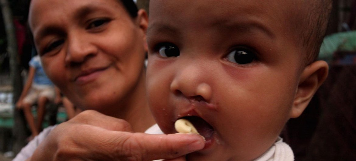 A mother in Mindanao, Philippines, feeds her baby with high-protein paste during a feeding programme for survivors of tropical storm Washi.