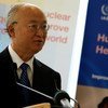 A man in a suit and glasses speaks at a podium during an event related to the IAEA and nuclear science for human health.