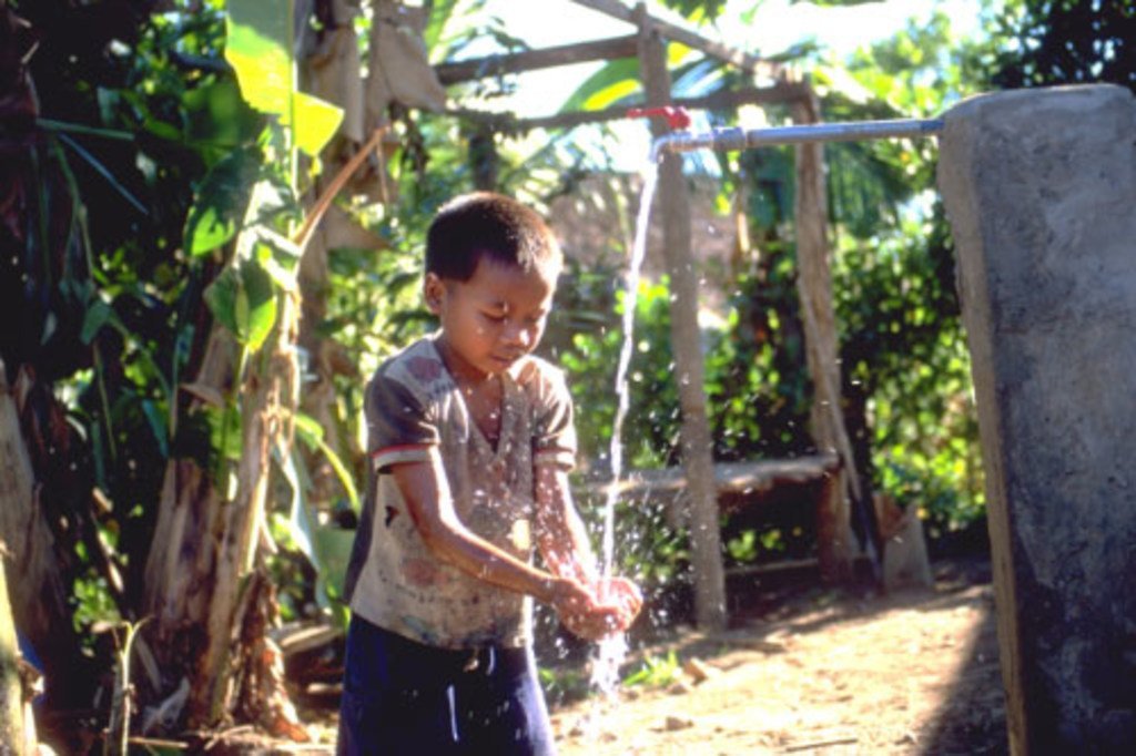 Un jeune garçon boit de l'eau fraîche d'un puits dans un village du nord du Laos.
