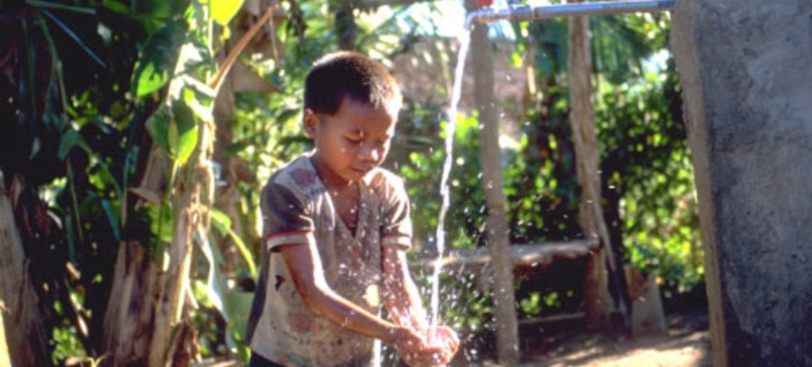 A young boy drinks fresh water from a well in a village in Northern Laos.