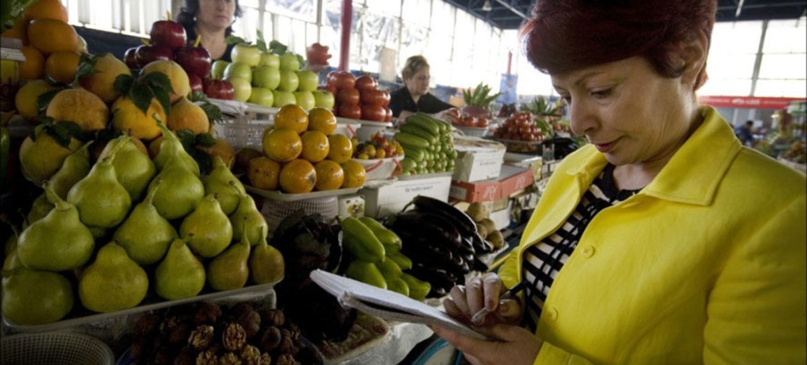Une femme achète de la nourriture sur un marché. Photo FAO/J. Spanner