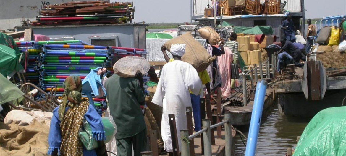 Returnees to South Sudan loading their belongings onto a barge at the wharf in Kosti.