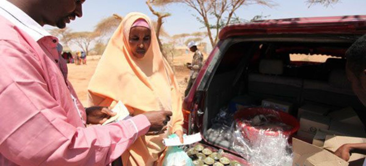 A mother buys canned fish from a local vendor using a WFP food voucher in Burao, northern Somalia.