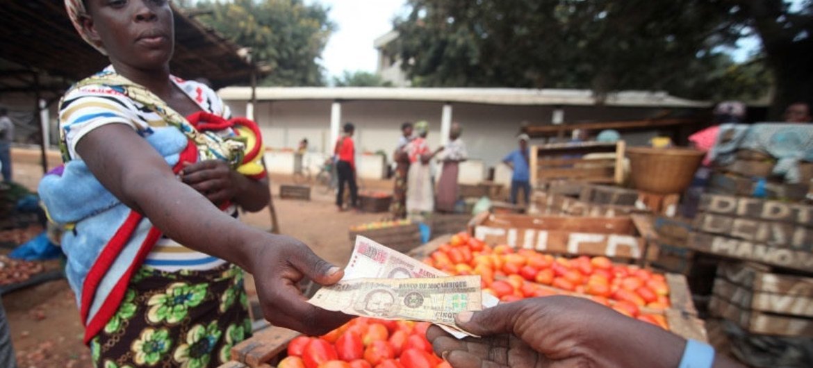 Une femme achète des tomates sur un marché local.