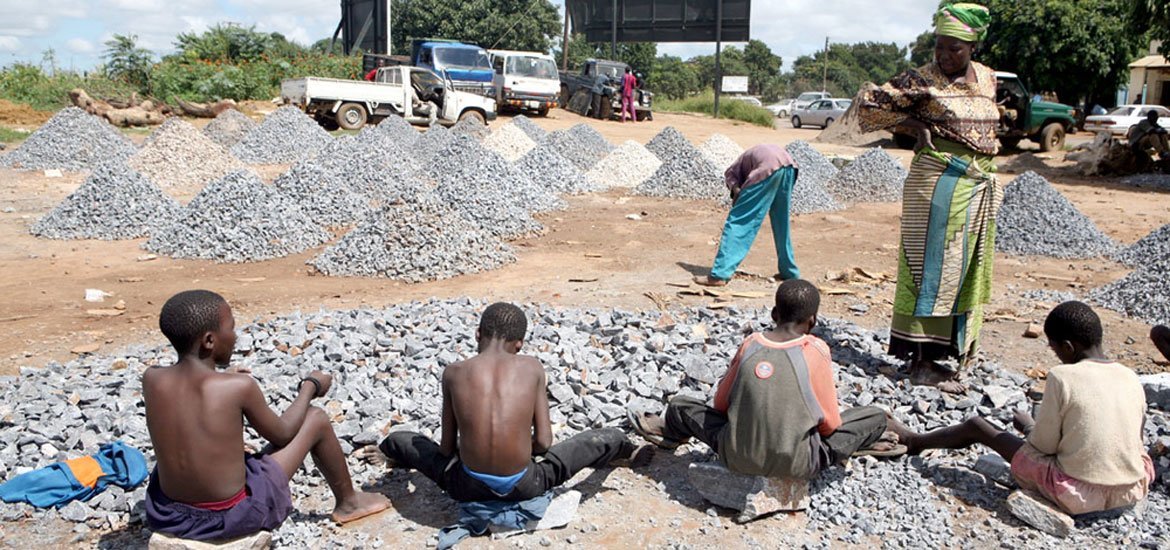 A woman watches children working at a stone quarry, Zambia. (file)