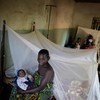 A mother and her baby beside an insecticide-treated bed net distributed by UNICEF.