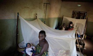 A mother and her baby beside an insecticide-treated bed net distributed by UNICEF.
