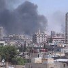 In Homs, Syria, smoke drifts into the sky from buildings and houses hit by shelling.