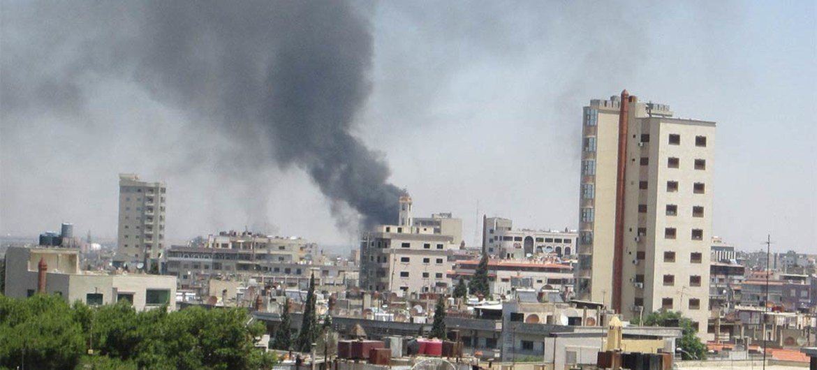Smoke drifts into the sky from buildings and houses hit by shelling in Homs, Syria (June 2012).