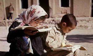 Young boy and girl reading books in a street in Qazvin, Iran.