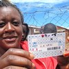 Une réfugiée dans le camp de Dzaleka au Malawi brandit sa carte de rationnement alimentaire du PAM.