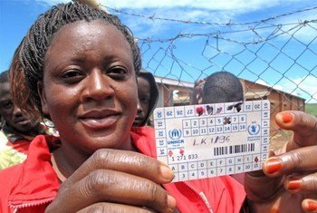 A refugee at Dzaleka camp in Malawi holds up her food ration card from WFP.