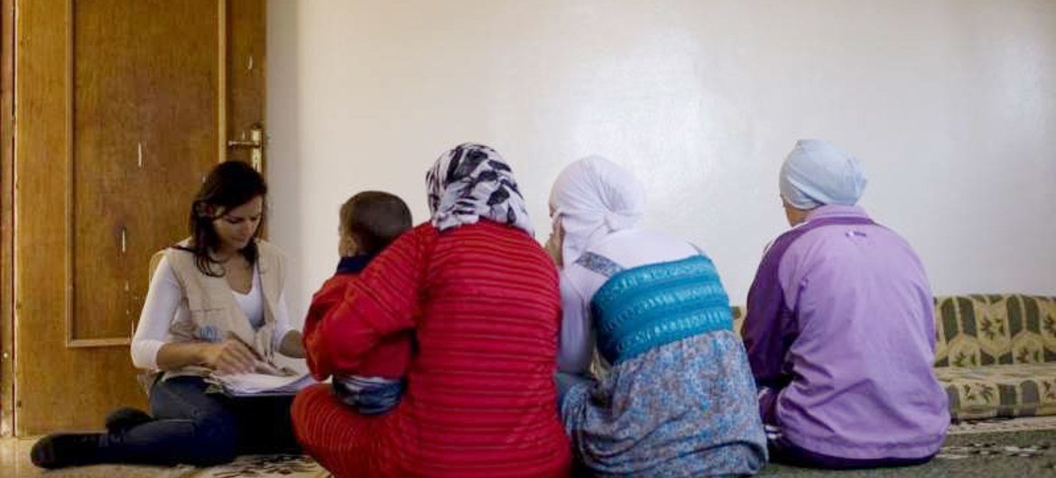 Une employée du HCR sur le terrain enregistre une famille syrienne déracinée au Liban.