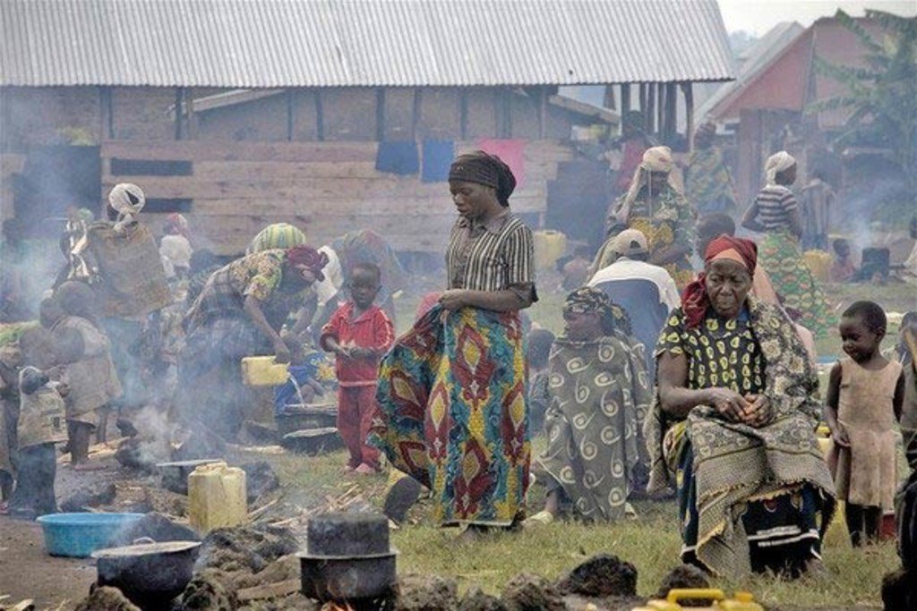 Des femmes et des enfants cuisinent en plein air dans un village rural de la République démocratique du Congo.