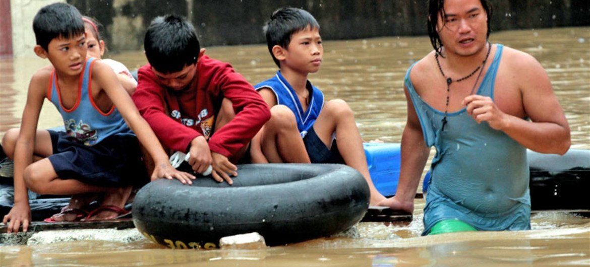 Four young children are rescued with the use of inner tubes at a flooded riverside community in Manila.