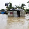 A resident of a low-lying area of Port-au-Prince flees his flooded home taking whatever possessions with him.