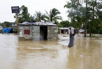 A resident of a low-lying area of Port-au-Prince flees his flooded home taking whatever possessions with him.