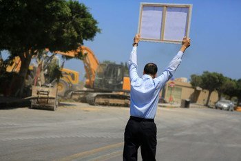 A lone protester holds up a placard condemning the destruction of a Sufi shrine in Tripoli as he approaches the site of the demolition.