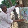 Health worker during community awareness campaign, showing guinea worm disease flipchart.