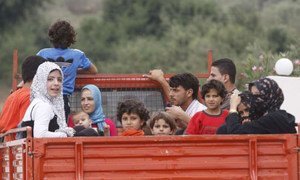 A Syrian family gets a lift at a crossing to Lebanon where they will register at UNHCR centres.