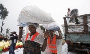 At the Kanyaruchinya internally displaced persons camp in Goma, women carry large bags of food rations distributed by UNICEF.