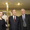 Secretary-General Ban Ki-moon, holding Olympic torch, is flanked by Amb. Mark Lyall Grant of the United Kingdom (right) and Olympic gold medalist Sarah Hughes.