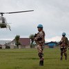 MONUSCO peacekeepers and FARDC elements on joint patrol in Bunagana, North Kivu, DRC, while a UN helicopter hovers.