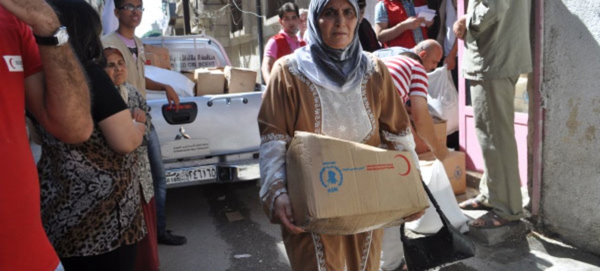 Une femme à Damas, en Syrie, reçoit des rations alimentaires de la part du PAM.
