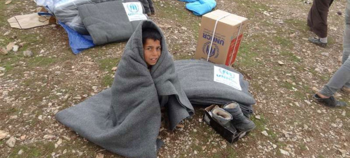 Un jeune réfugié syrien tente de se réchauffer à l'aide d'une couverture au nord de l'Iraq.