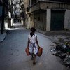 A girl carrying jerrycans of water, walks past a pile of debris on a street in Aleppo, Syria. UNICEF/NYHQ2012-1293/Romenzi