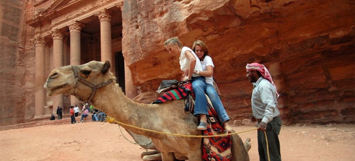 Turistas subiéndose a un camello en Petra, en Jordania.