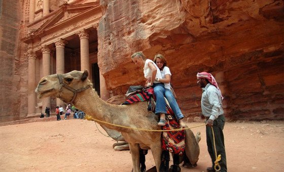 Tourists ride a camel in Petra, Jordan.